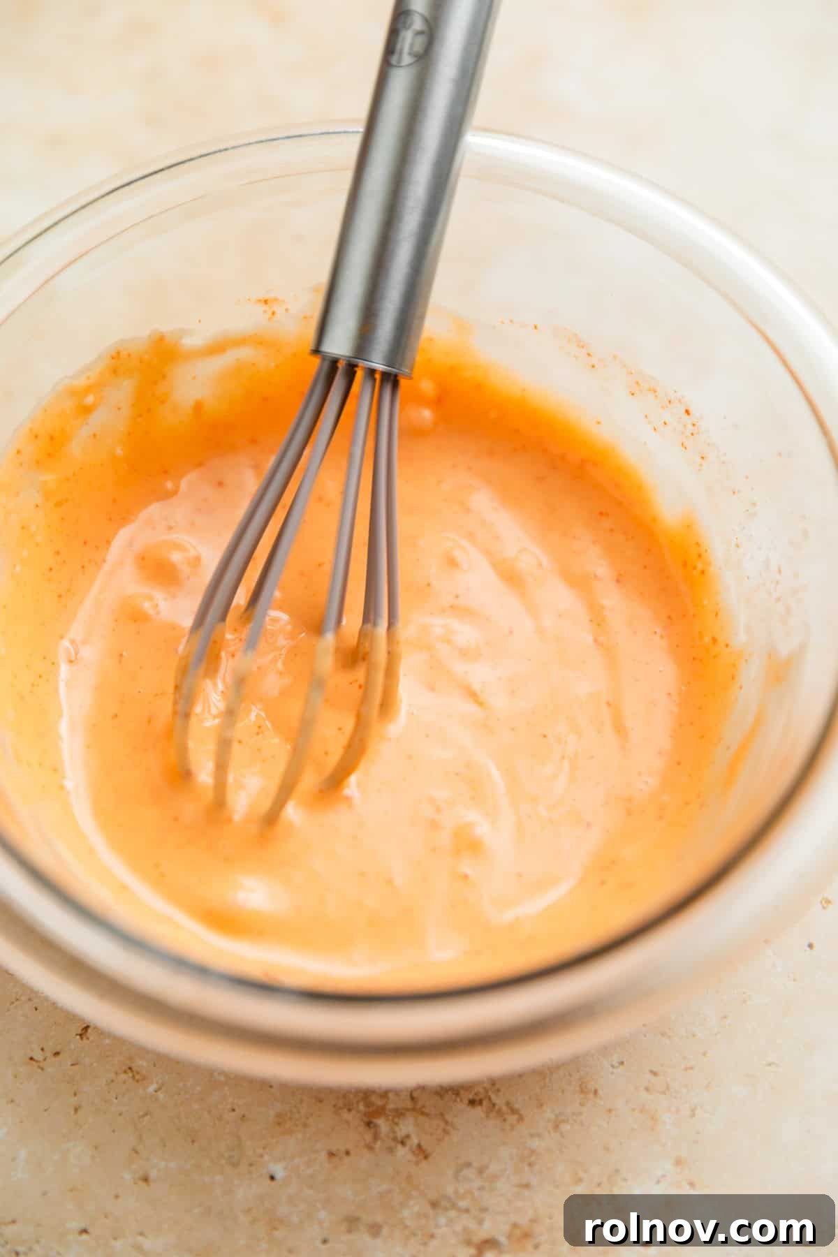 Savory Turkey Rice Power Bowls 5 Bang bang sauce, perfectly mixed, sits in a glass bowl with a whisk, ready to be chilled and served.