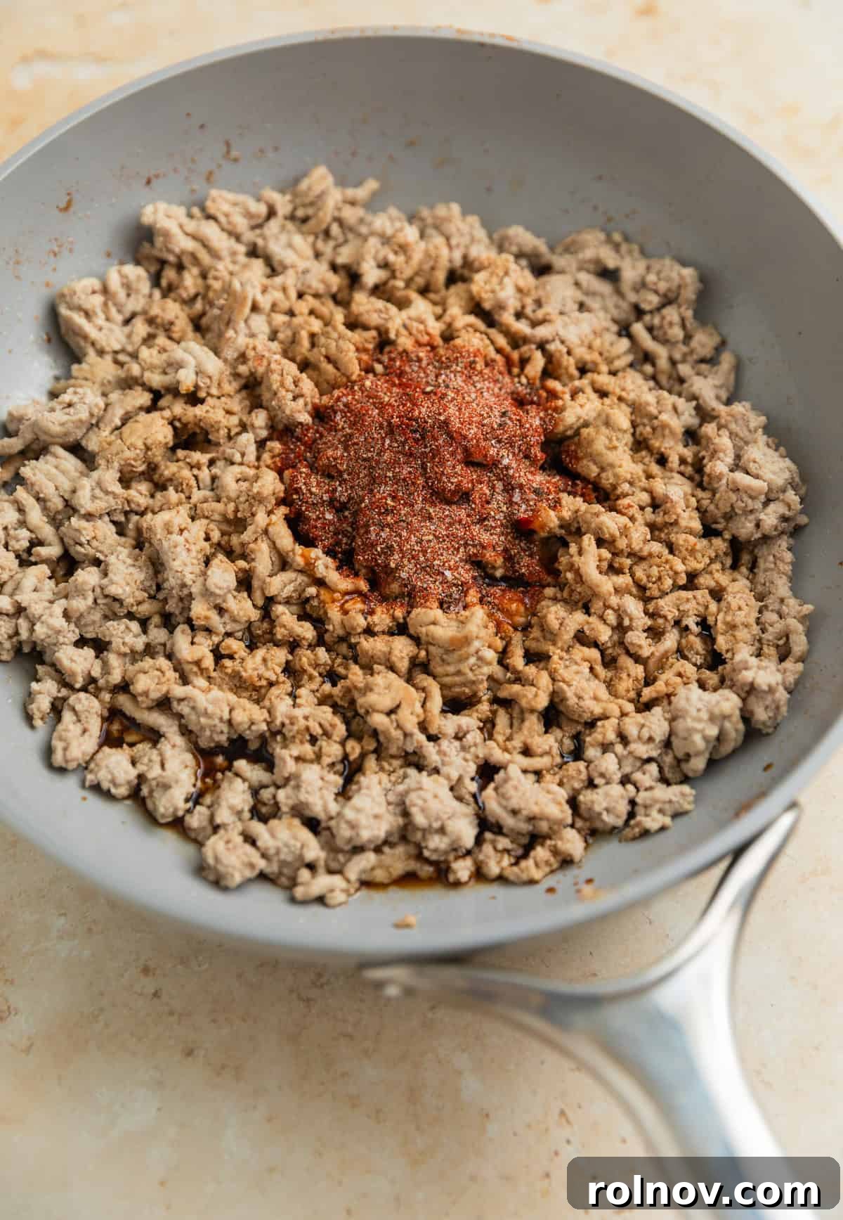 Savory Turkey Rice Power Bowls 6 Ground turkey browning in a skillet, with various seasonings being added to infuse flavor during the cooking process.