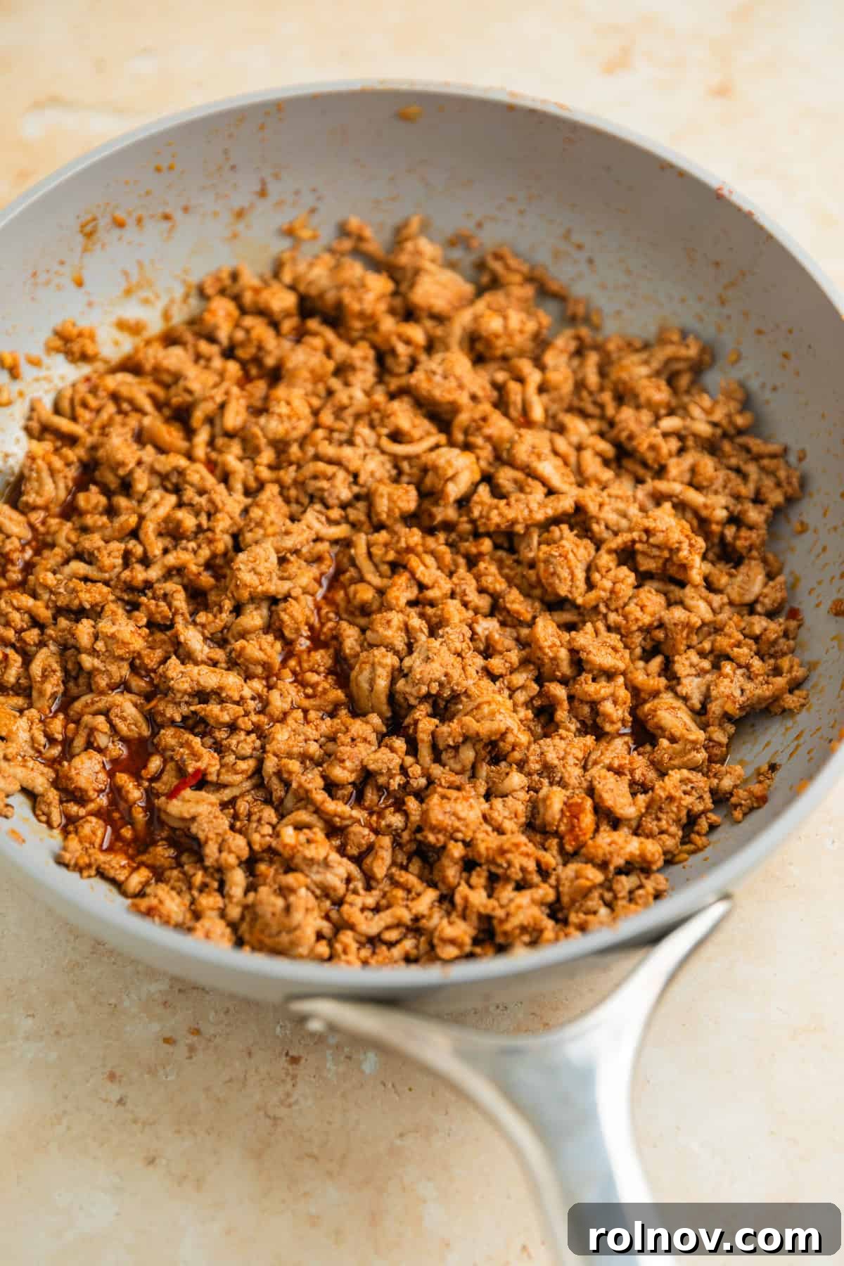 Savory Turkey Rice Power Bowls 7 A close-up of ground turkey simmering in a rich, savory sauce in a skillet, showcasing its delicious aroma and texture.