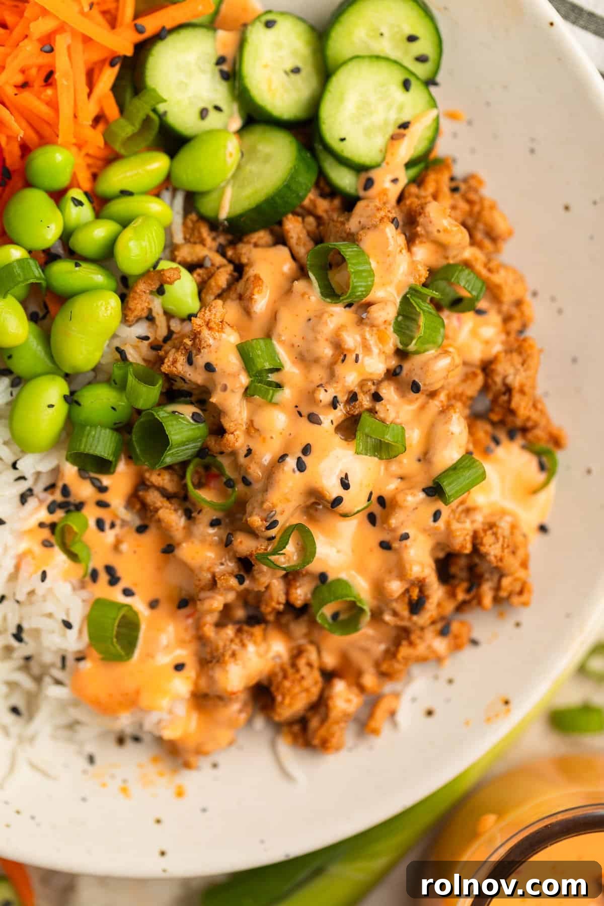 Savory Turkey Rice Power Bowls 8 A mouthwatering ground turkey mixture served in a bowl with fluffy rice, edamame, crisp cucumber slices, and a rich drizzle of bang bang sauce.