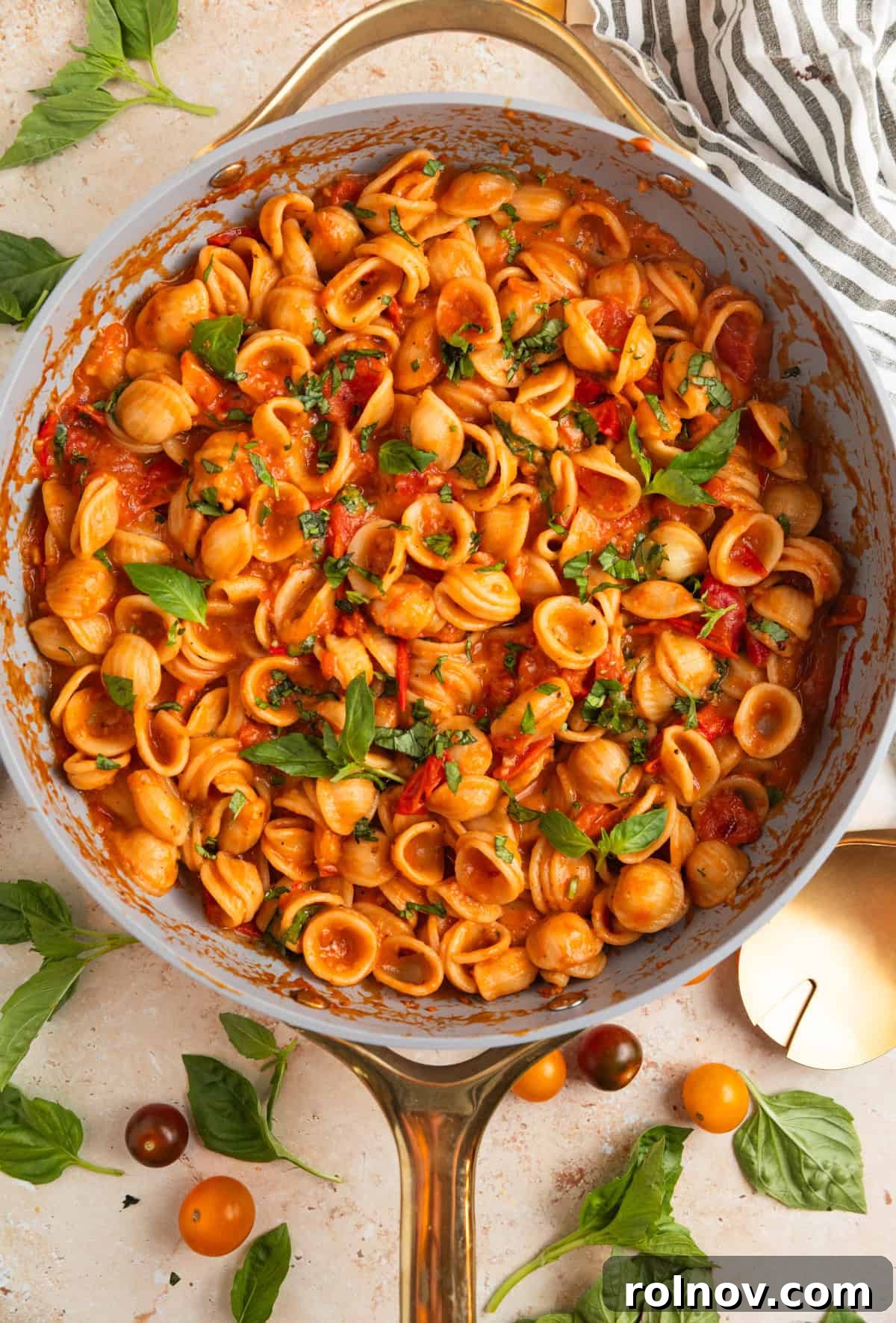 Sun-Kissed Cherry Tomato Delight 9 Finished cherry tomato pasta in a pan, vibrant and steaming, generously garnished with a fresh handful of bright green basil leaves.