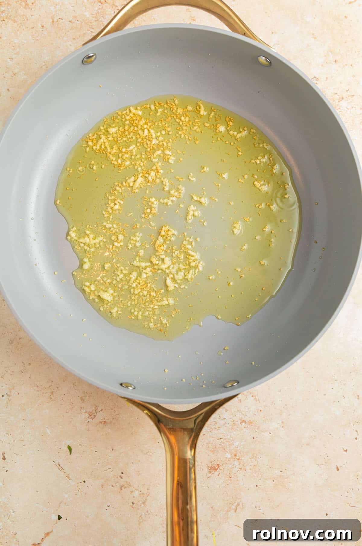 Sun-Kissed Cherry Tomato Delight 4 Olive oil glistening in a hot pan with minced garlic beginning to sauté, releasing its fragrant aroma before other ingredients are added.