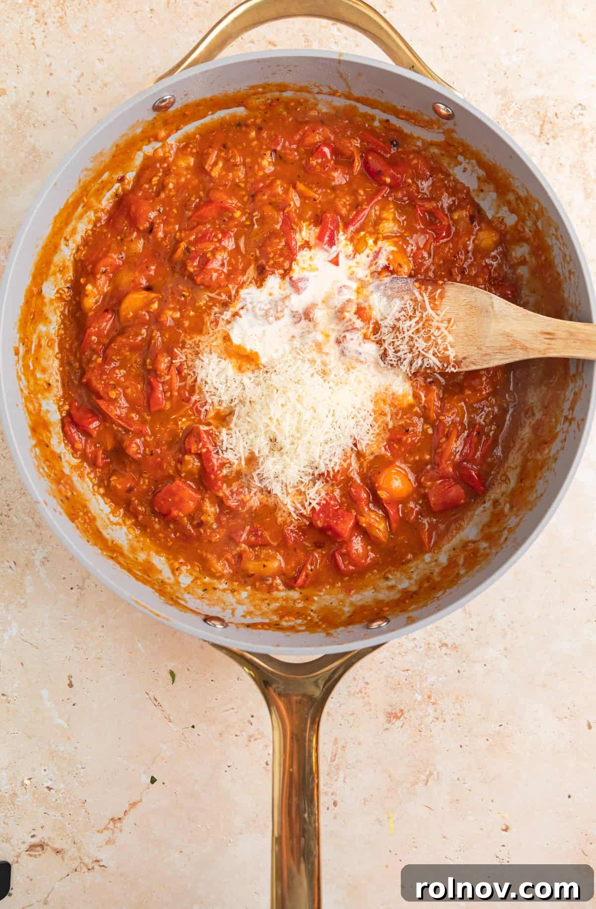 Sun-Kissed Cherry Tomato Delight 7 Creamy grated Parmesan cheese and rich heavy cream being stirred into the vibrant cherry tomato sauce in a skillet, creating a luscious and smooth texture.