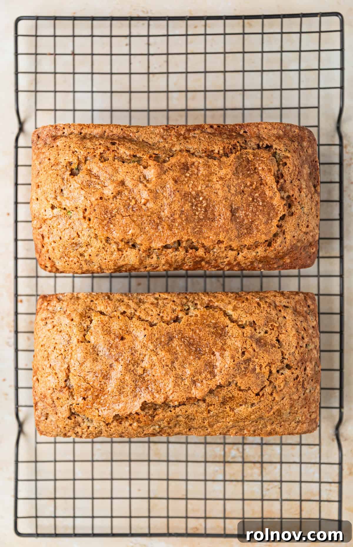 Grandmas Zucchini Bread Perfected 14 Two freshly baked loaves of zucchini bread, golden brown and glistening, cooling on a wire rack.
