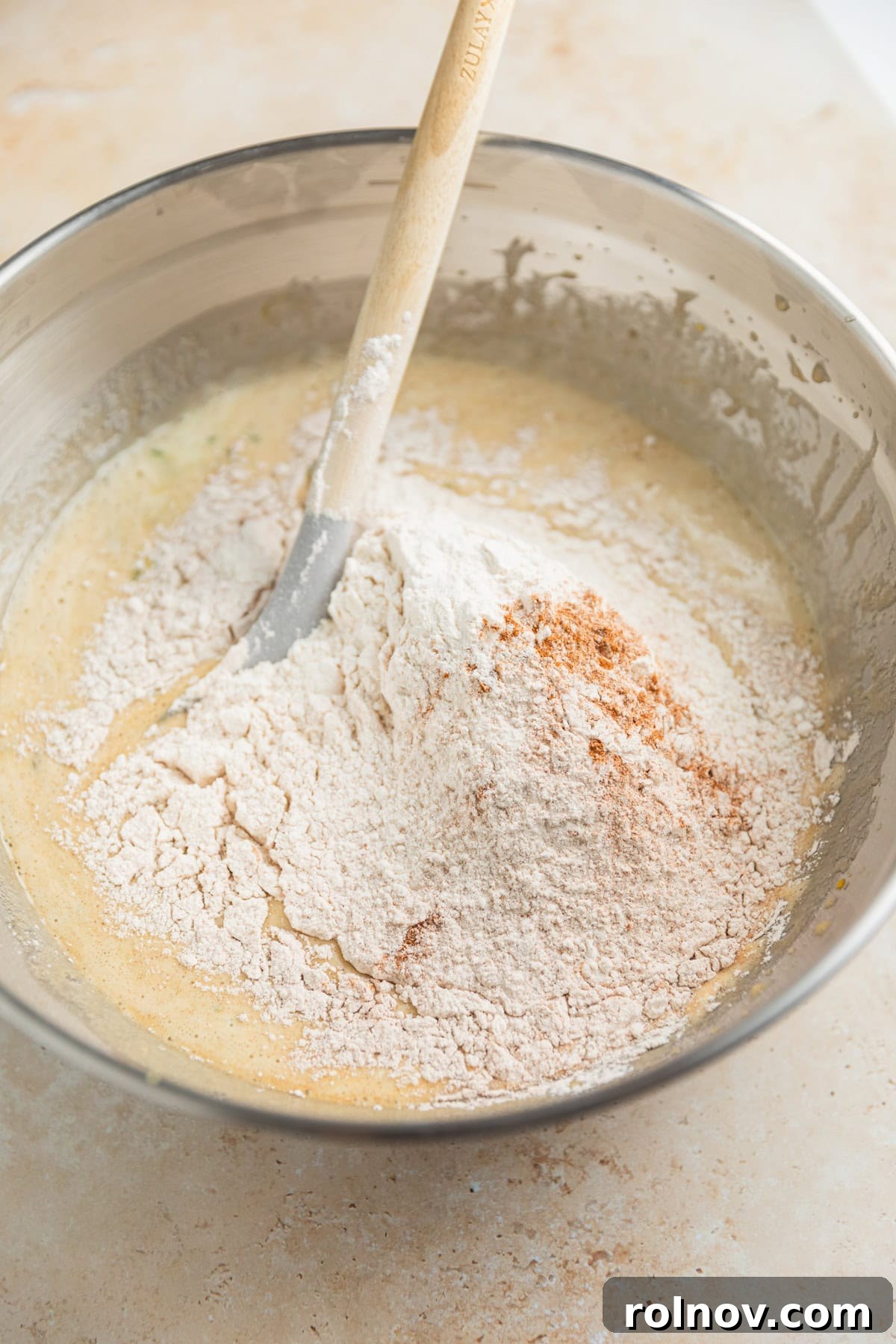Grandmas Zucchini Bread Perfected 9 Dry ingredients being gently folded into the wet batter mixture in a large glass bowl.