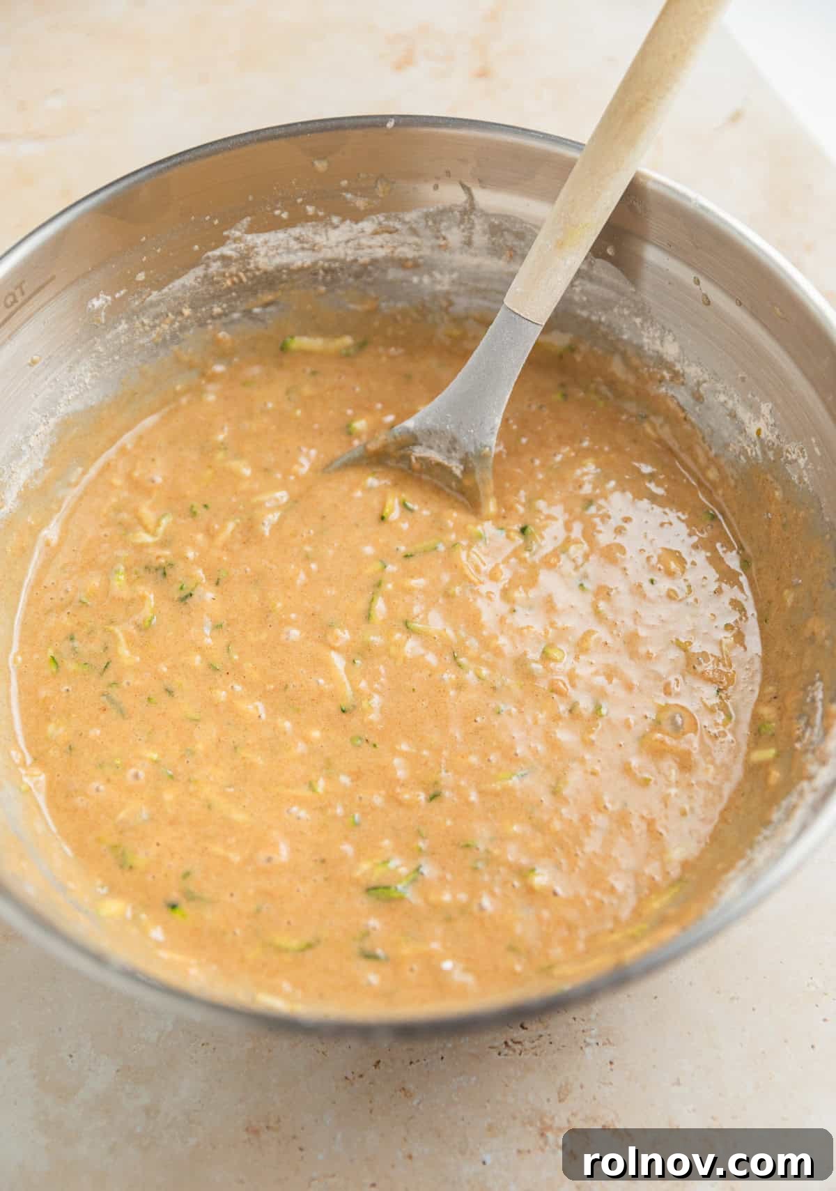 Grandmas Zucchini Bread Perfected 10 A rich, thick zucchini bread batter in a mixing bowl with a wooden spoon, ready for add-ins.