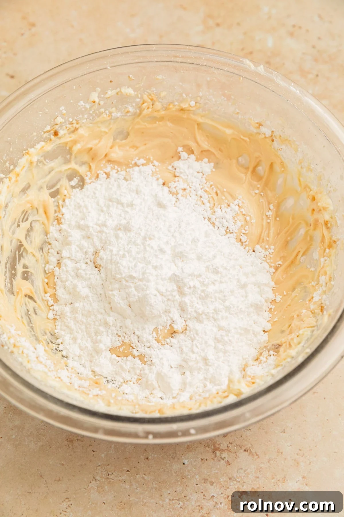 Effortless Cake Mix Pumpkin Bread 13 Powdered sugar being gradually added to the cream cheese frosting mixture in a bowl, in preparation for blending.