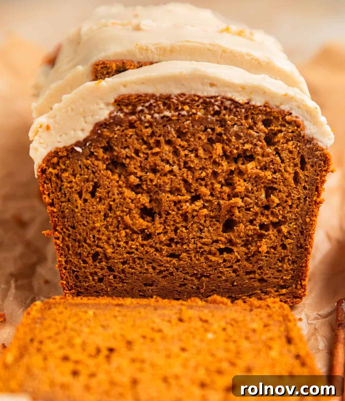 Effortless Cake Mix Pumpkin Bread 15 A beautifully frosted pumpkin bread loaf with a slice already removed, showcasing its moist texture and generous frosting.