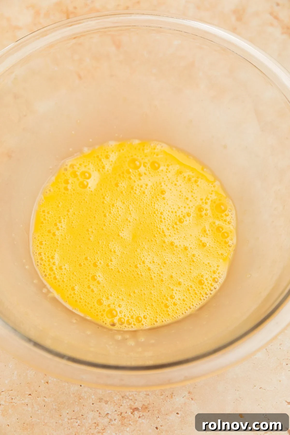 Effortless Cake Mix Pumpkin Bread 5 Freshly whisked eggs in a clear glass bowl, slightly frothy and ready for other ingredients.