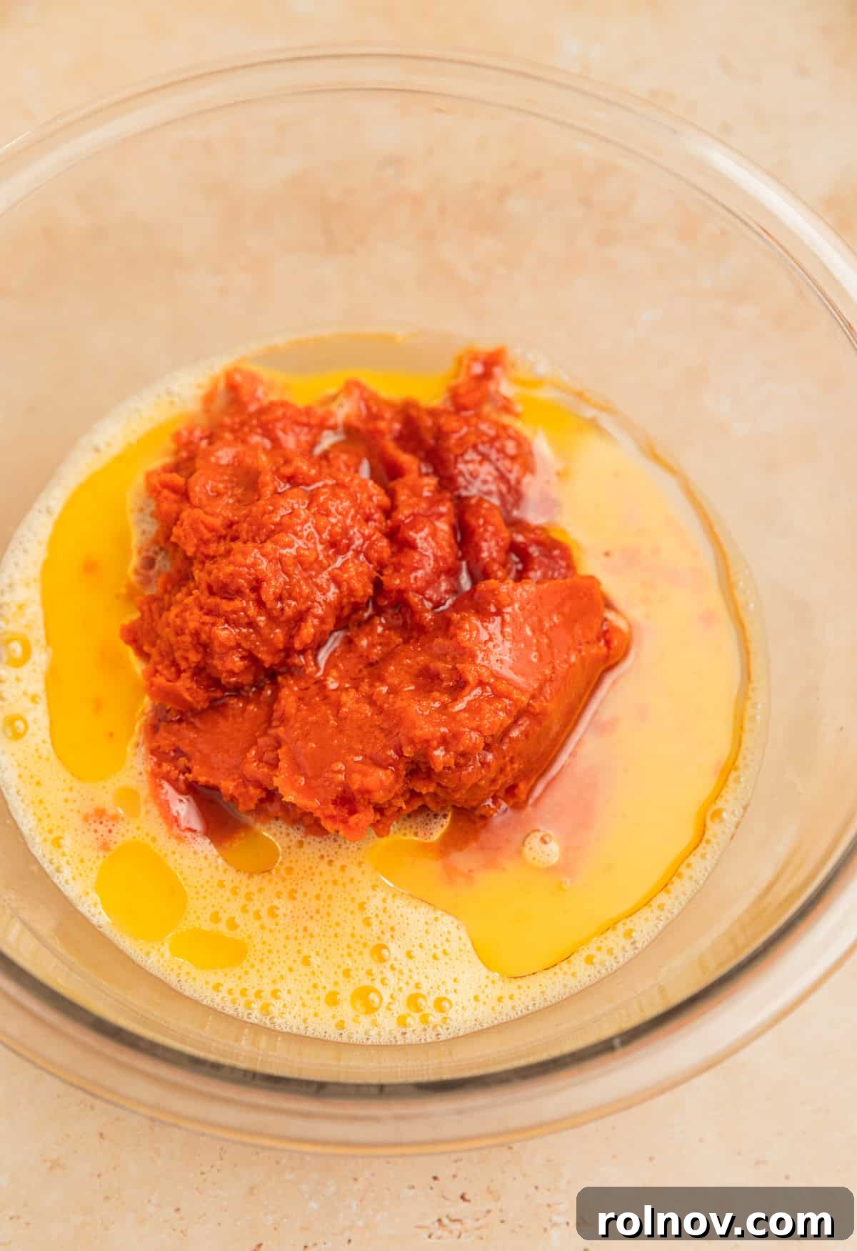Effortless Cake Mix Pumpkin Bread 6 Canned pumpkin puree, cooking oil, milk, and other liquid ingredients being added to a mixing bowl with whisked eggs.