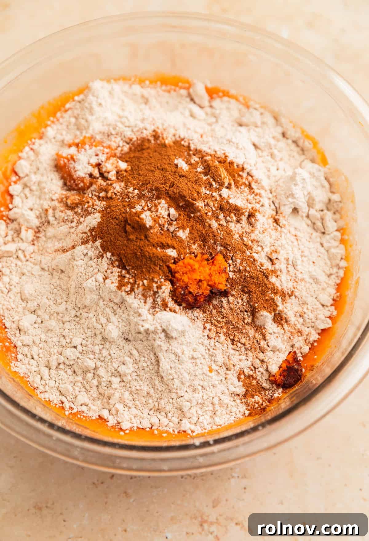 Effortless Cake Mix Pumpkin Bread 8 Spice cake mix, pumpkin pie spice, and fresh orange zest added on top of the pumpkin wet mixture in a mixing bowl.