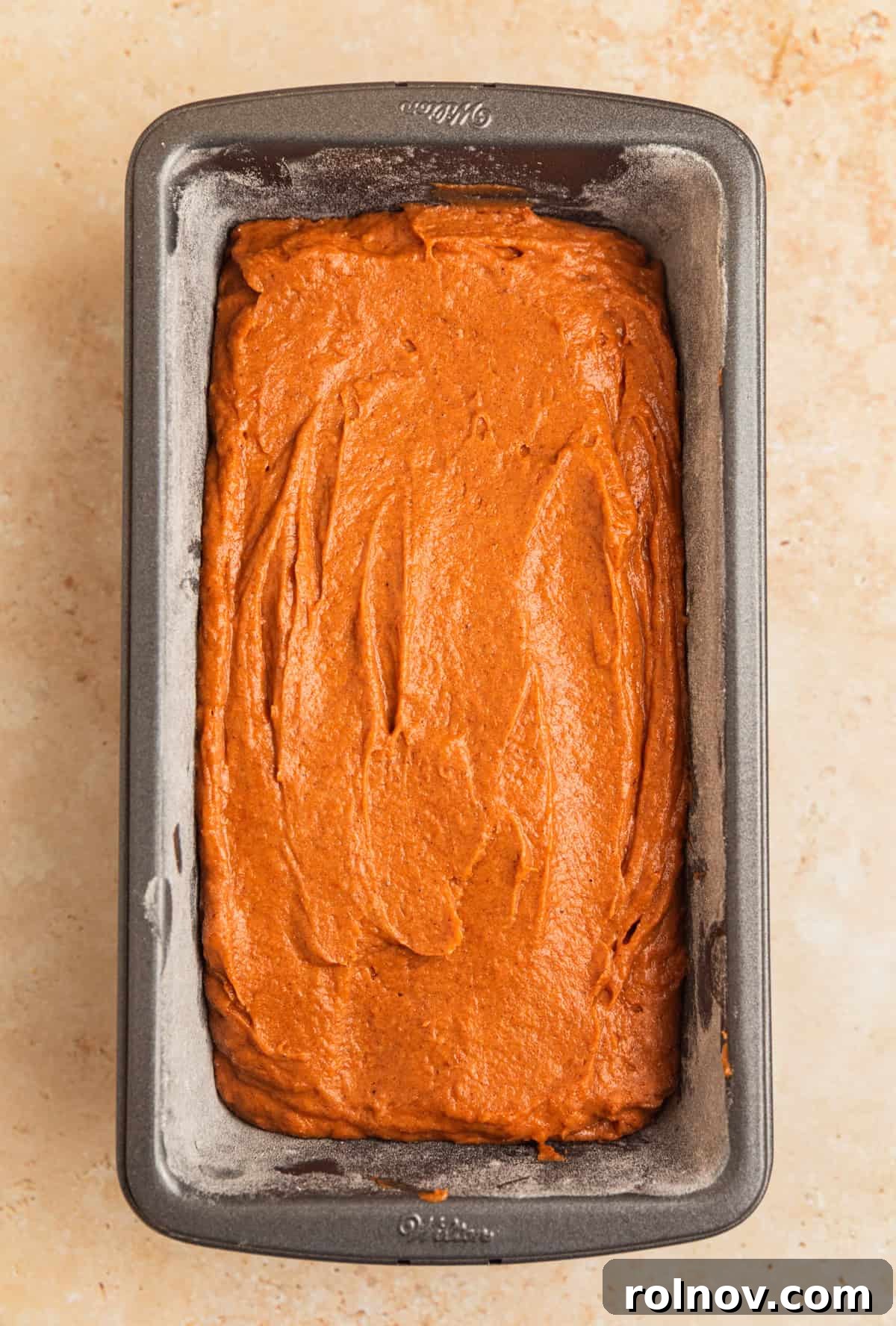Effortless Cake Mix Pumpkin Bread 10 The smooth pumpkin bread batter poured into a meticulously greased and floured loaf pan, ready for baking.