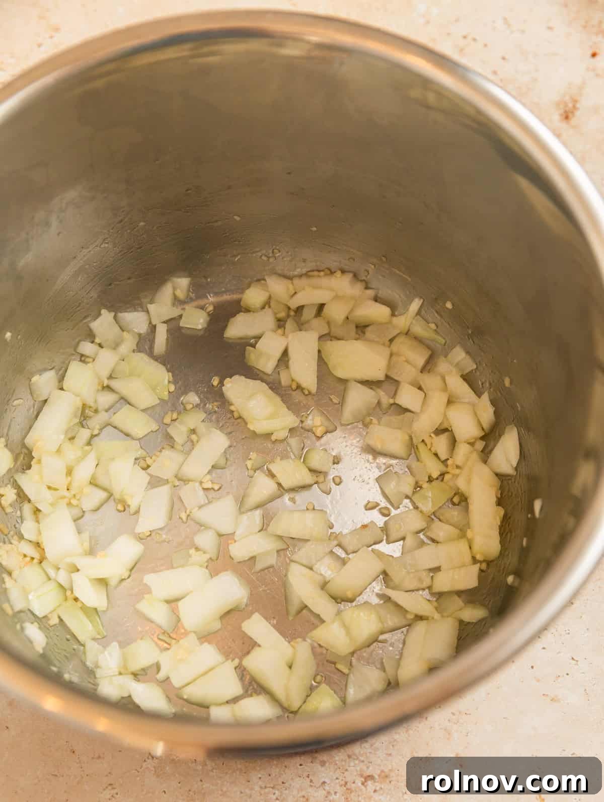 One-Pot Wonder Spaghetti 5 Instant Pot interior with finely diced onions being sautéed until soft and translucent, preparing the aromatic base for the spaghetti sauce.
