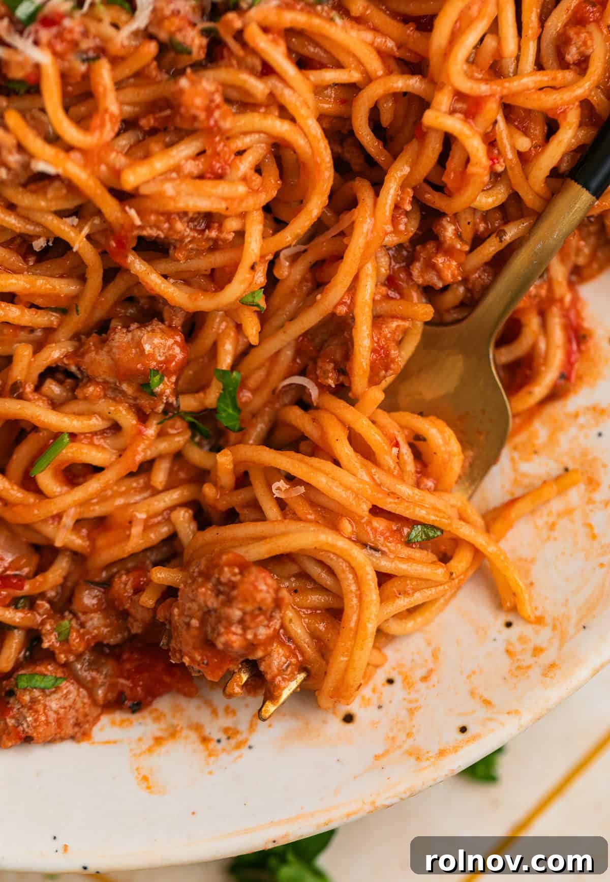 One-Pot Wonder Spaghetti 10 A fork lifts a generous serving of Instant Pot spaghetti with rich meat sauce from a white plate, highlighting the delicious texture and sauciness.