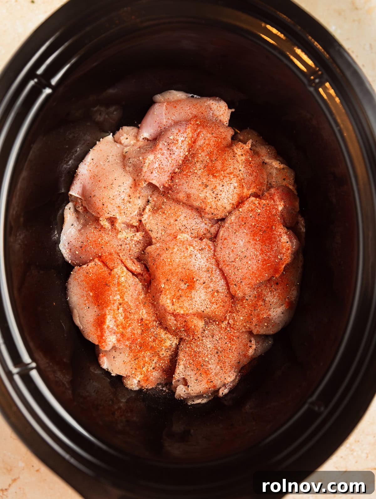 Sweet and Savory Apricot Slow-Cooked Chicken 4 Chicken thighs in crockpot with seasoning on top.