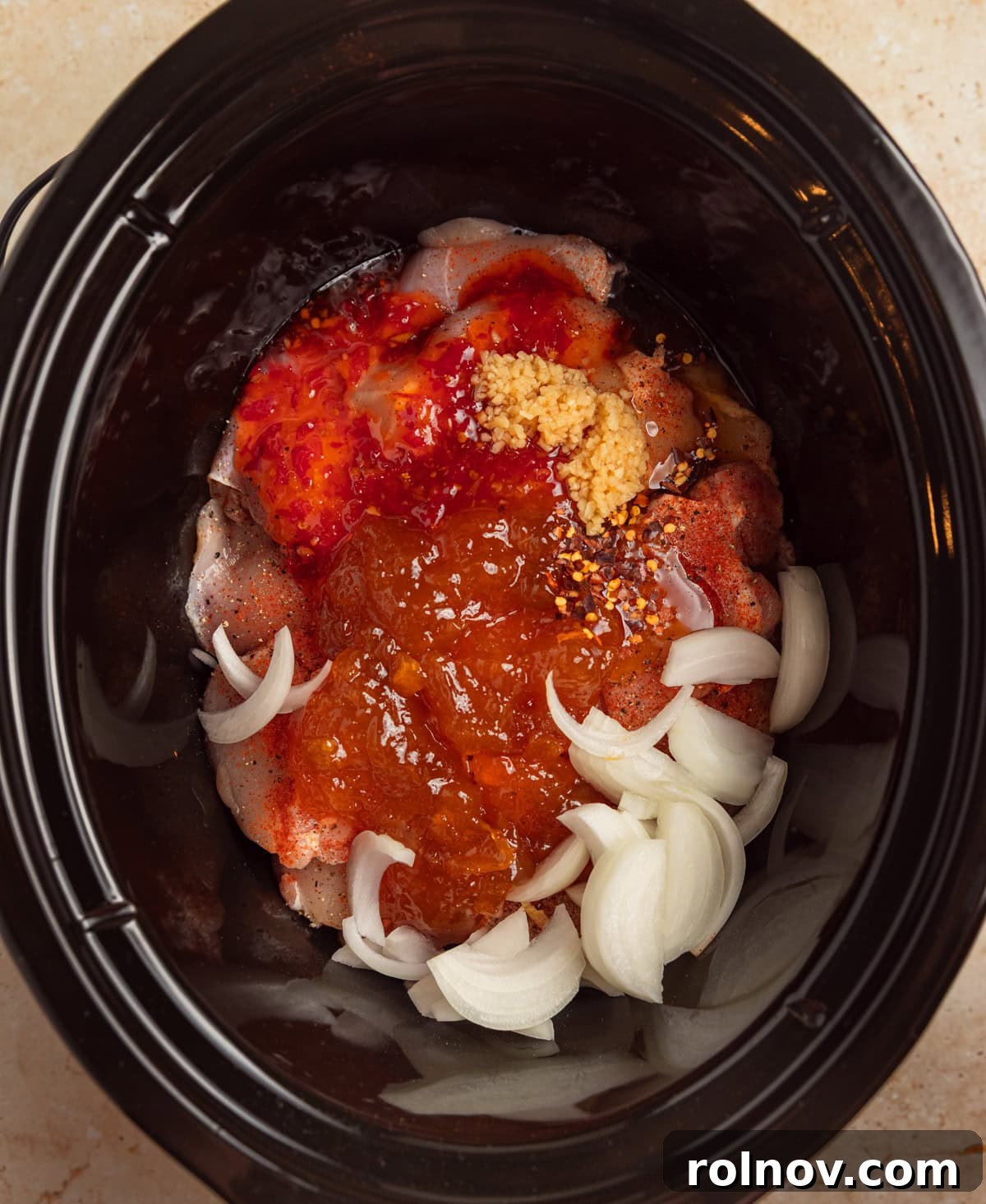 Sweet and Savory Apricot Slow-Cooked Chicken 5 Slow cooker with apricot preserves, onion and seasoning over chicken.