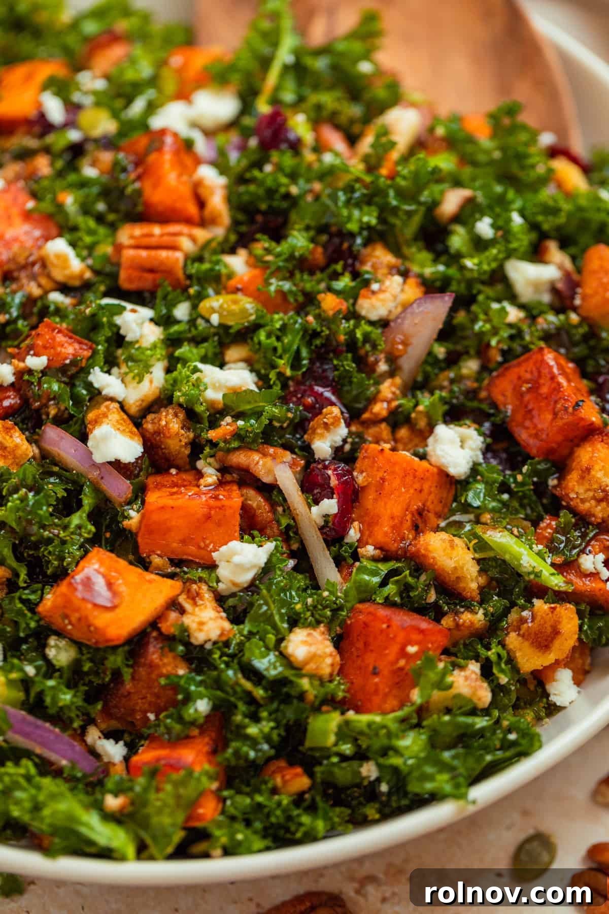 Roasted Sweet Potato Kale Salad 2 Vibrant Sweet potato kale salad in a rustic serving platter, adorned with crumbled feta, golden cornbread croutons, and fresh herbs, ready to be enjoyed.