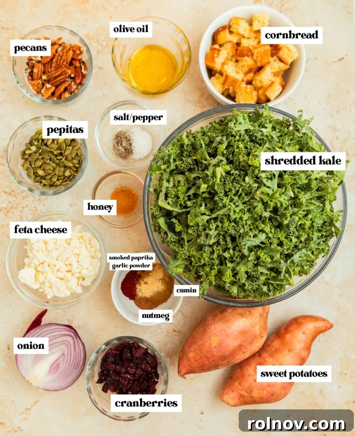 Roasted Sweet Potato Kale Salad 4 An organized display of fresh shredded kale in a glass bowl, alongside golden cornbread cubes, crumbled feta cheese, and vibrant sweet potato pieces, ready for salad preparation.