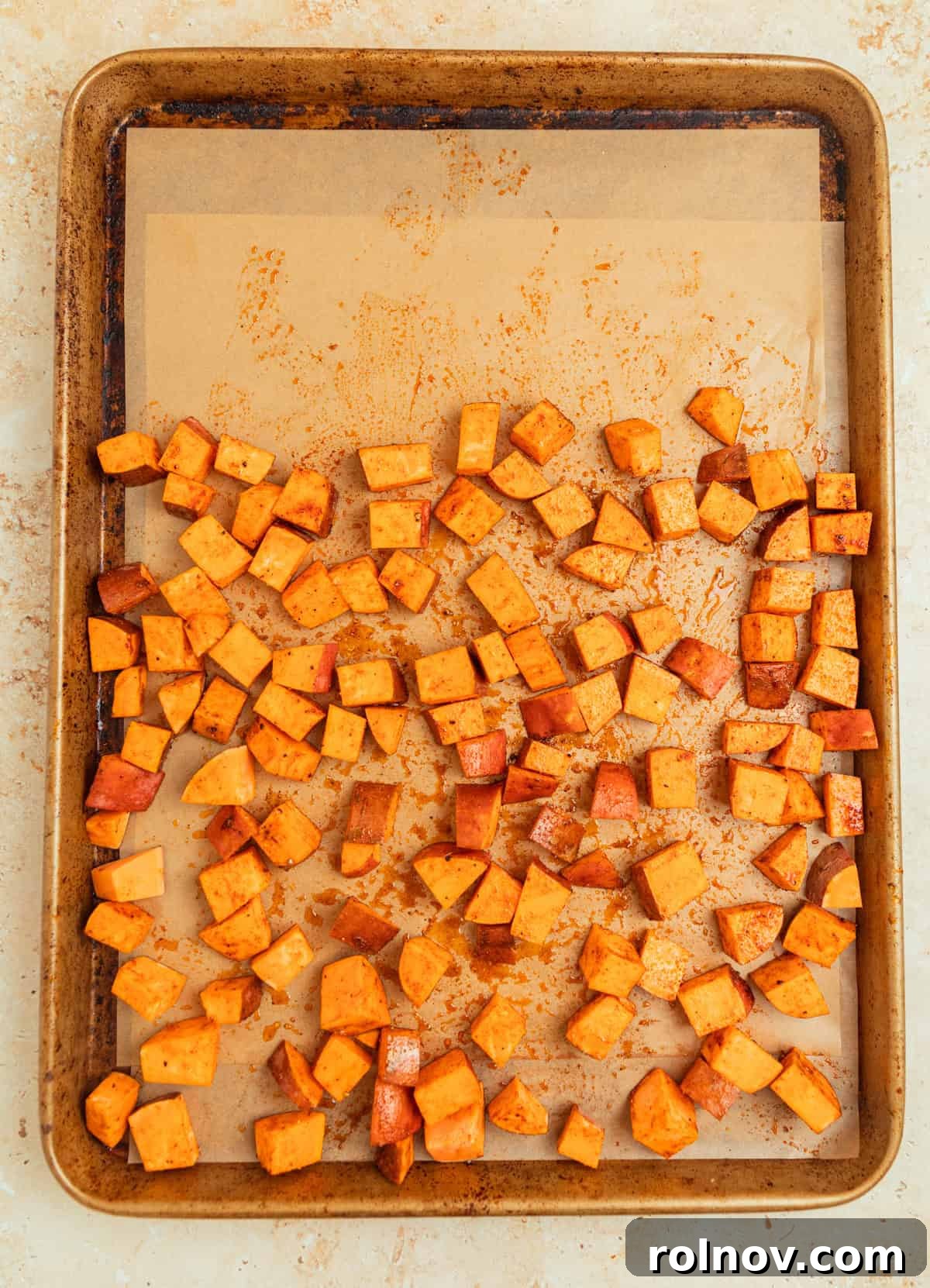 Roasted Sweet Potato Kale Salad 5 Cubed sweet potatoes seasoned and spread evenly on a parchment-lined baking sheet, ready for roasting.