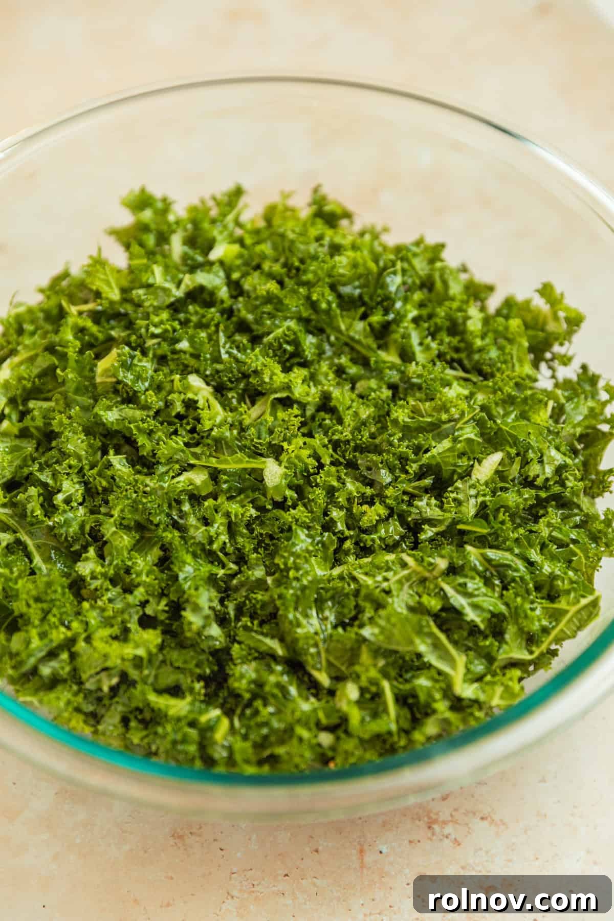 Roasted Sweet Potato Kale Salad 9 Finely chopped kale leaves being massaged with olive oil and sea salt in a large glass bowl, ready for salad assembly.