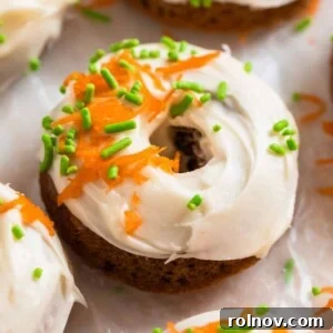 Carrot cake donut with cream cheese icing topped with sprinkles and shredded carrots.