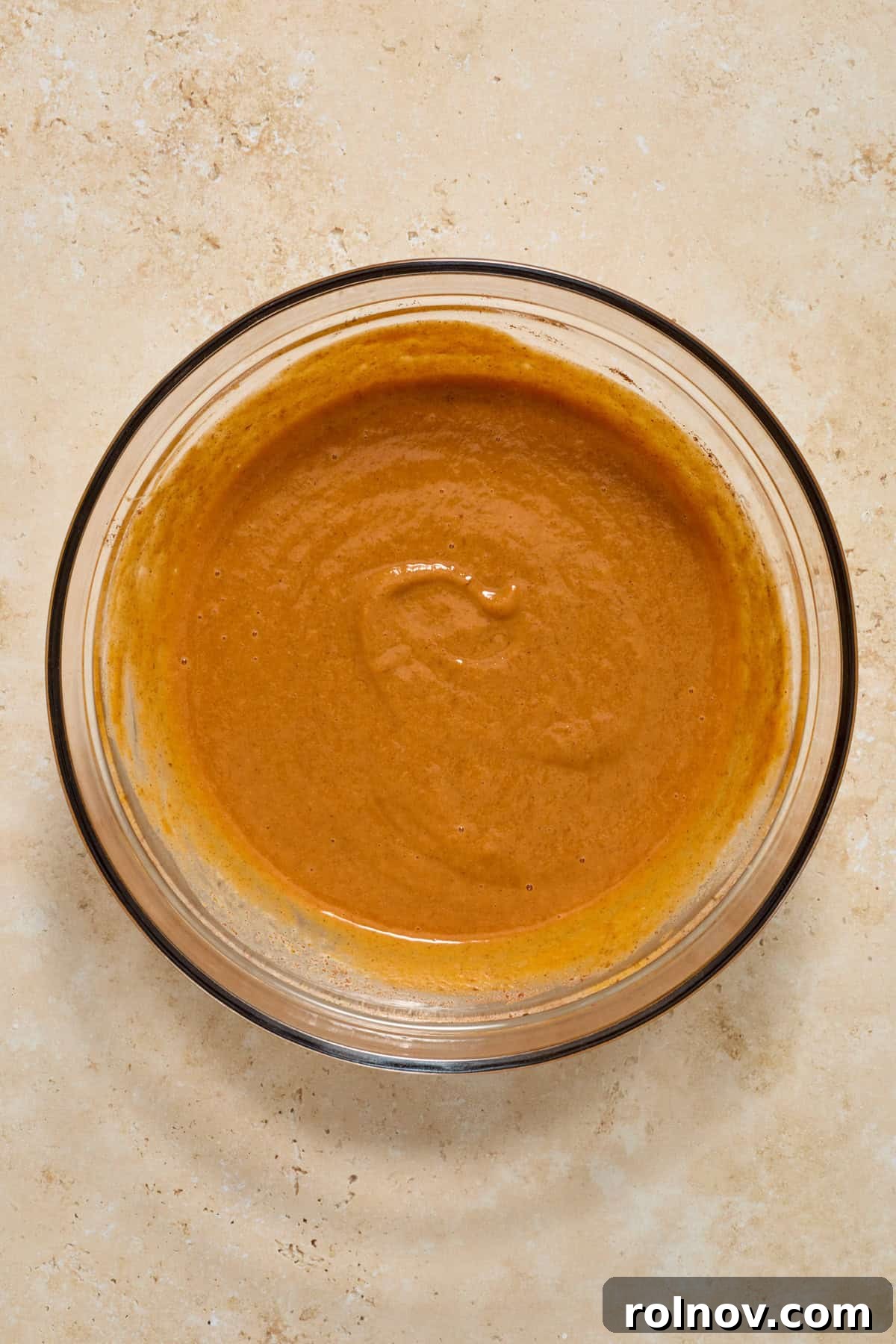Bite-Sized Pumpkin Delights 6 The pumpkin pie mixture, now smooth and creamy, rests in a clear glass bowl, showcasing its rich orange color.