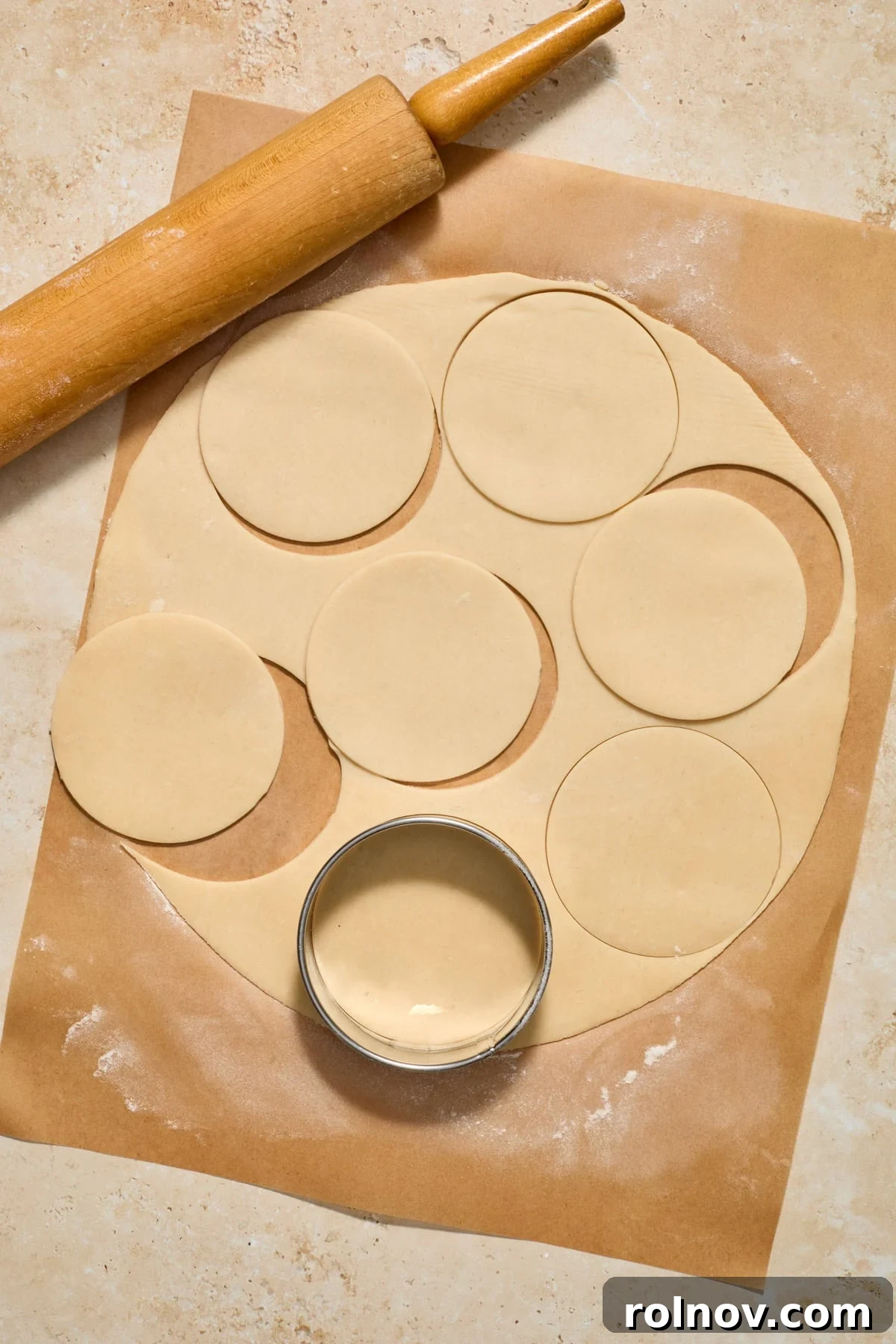 Bite-Sized Pumpkin Delights 7 Chilled pie crust rolled out on parchment paper with a rolling pin and a round biscuit cutter, ready to cut out rounds.
