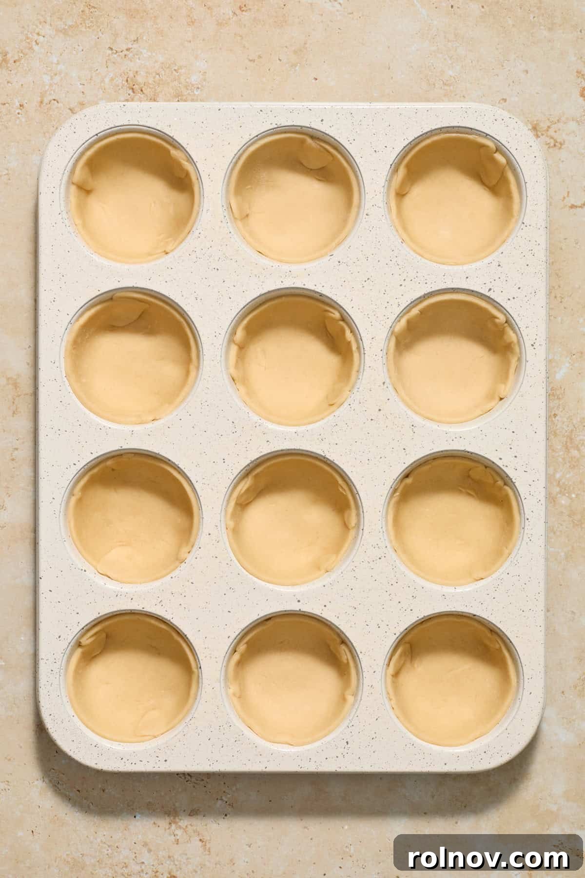 Bite-Sized Pumpkin Delights 8 A muffin tin with individual pie crust rounds pressed into each cavity, forming small cups.