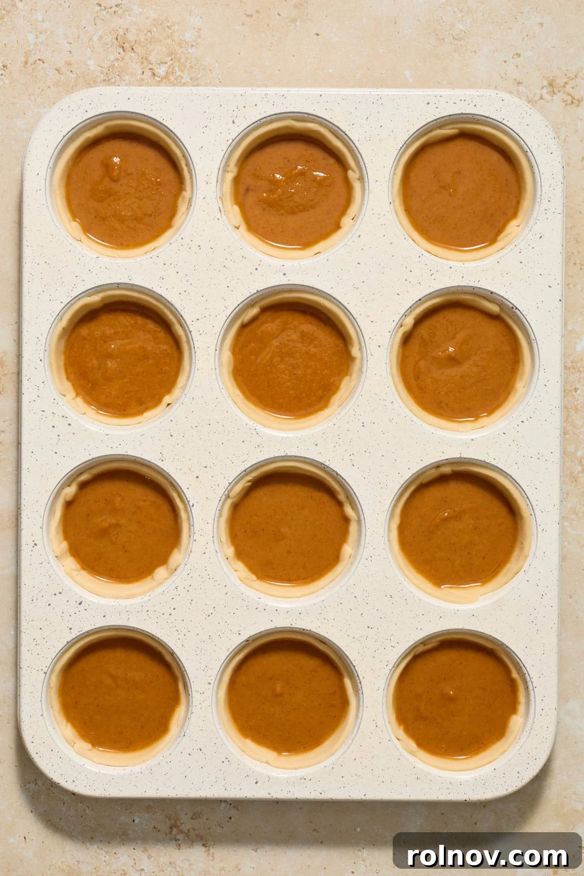 Bite-Sized Pumpkin Delights 9 A muffin tin filled with mini pumpkin pies, with the creamy pumpkin mixture spooned into each pie crust, before baking.