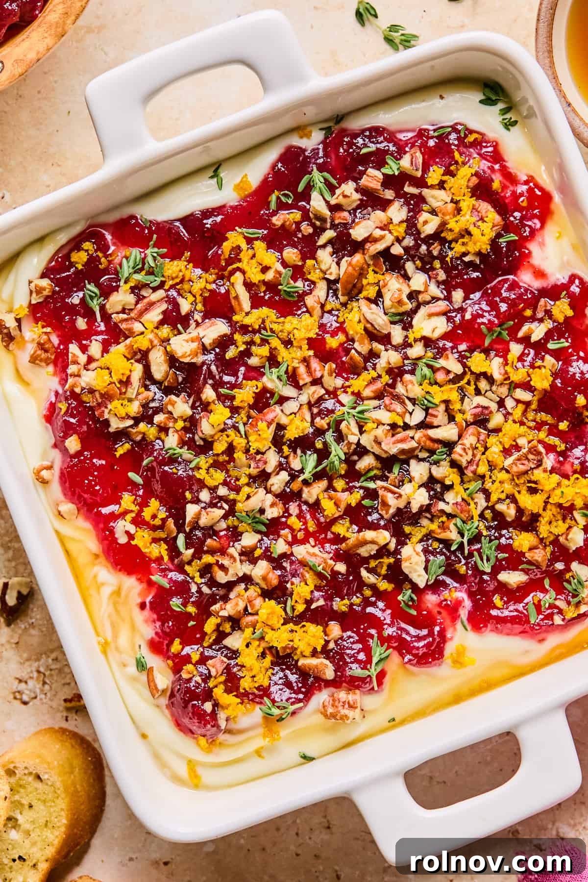 An inviting overhead shot of the cranberry whipped ricotta dip, garnished with pecans, thyme, and orange zest, ready for serving.
