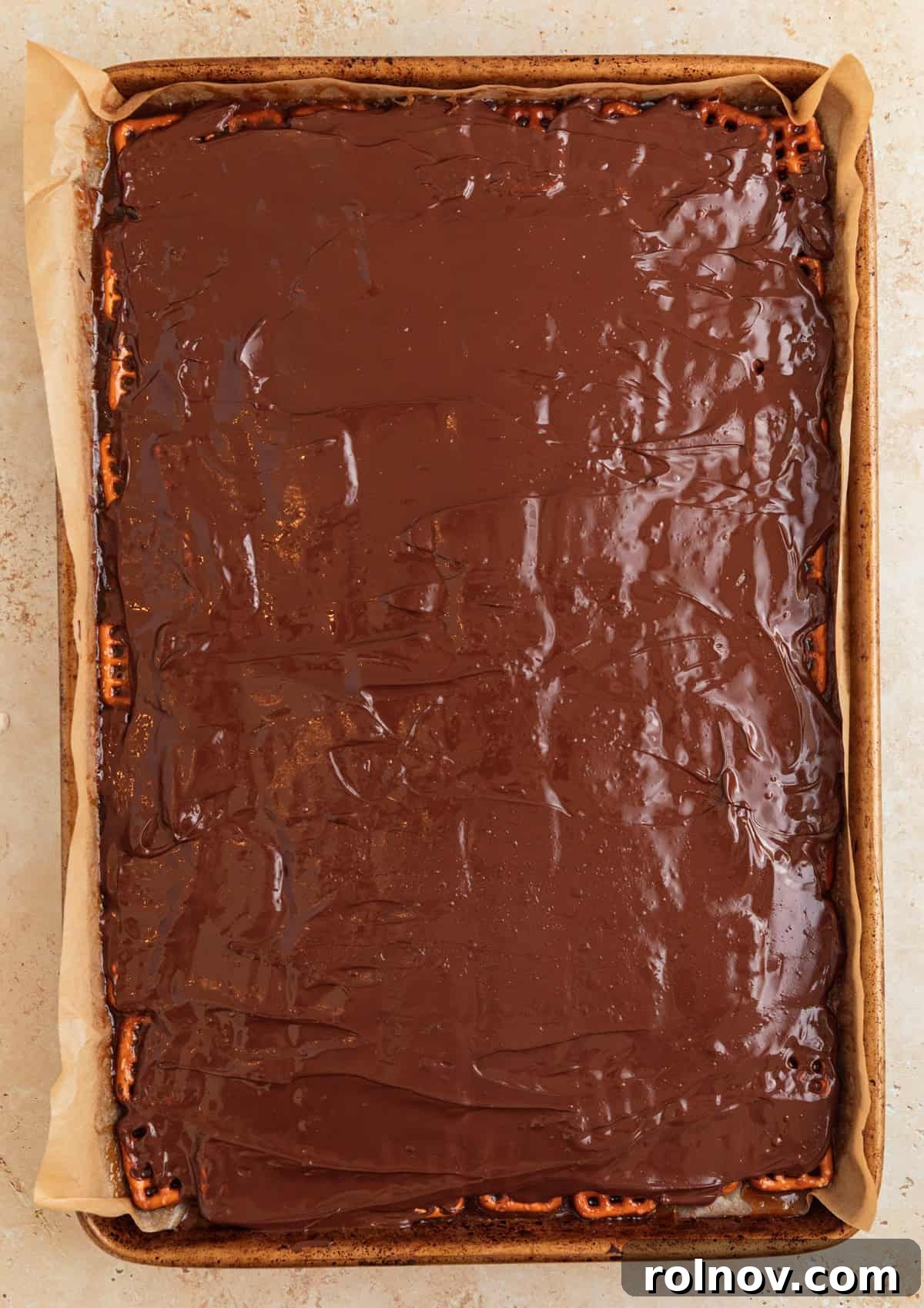 Salty Sweet Pretzel Toffee Crunch 11 Melted chocolate chips smoothly spread to cover the entire surface of the pretzel toffee, creating an even, glossy layer.