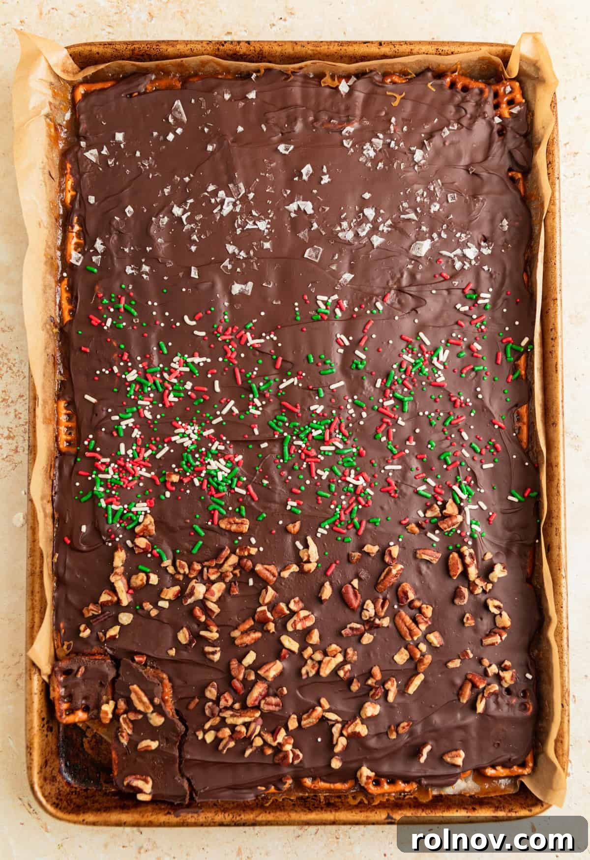 Salty Sweet Pretzel Toffee Crunch 12 Chilled pretzel toffee, broken into irregular pieces, adorned with chopped pecans, flaky sea salt, and festive red and green sprinkles, showcasing its completed, tempting form.