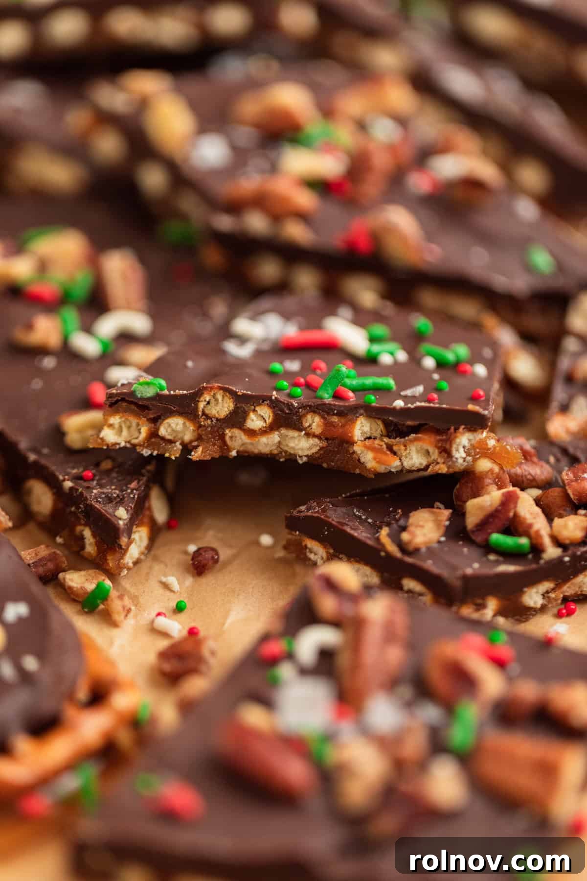 Salty Sweet Pretzel Toffee Crunch 13 Broken pieces of Christmas pretzel toffee, showcasing its crisp texture, rich layers of caramel and chocolate, and delightful toppings on parchment paper.