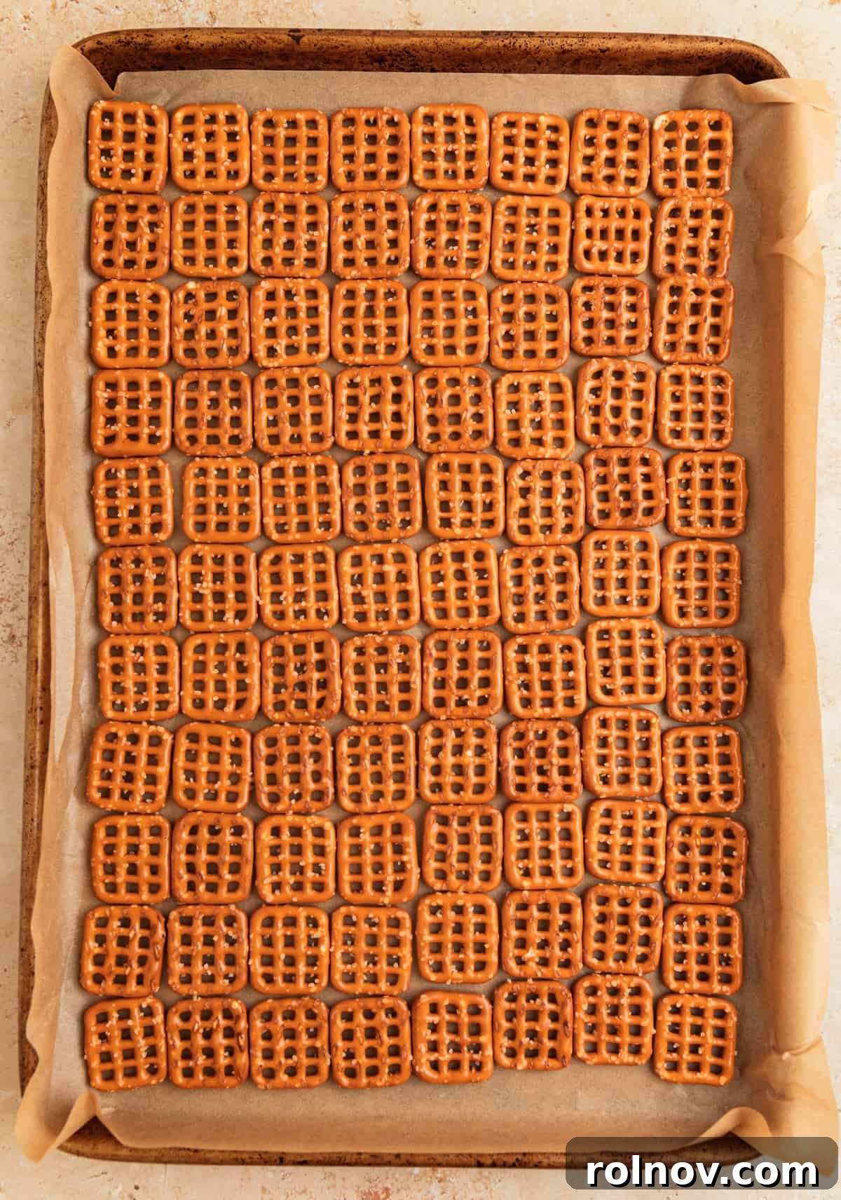 Salty Sweet Pretzel Toffee Crunch 5 Pretzels perfectly lined up in a grid pattern on a parchment-lined baking sheet, forming the base for the toffee.