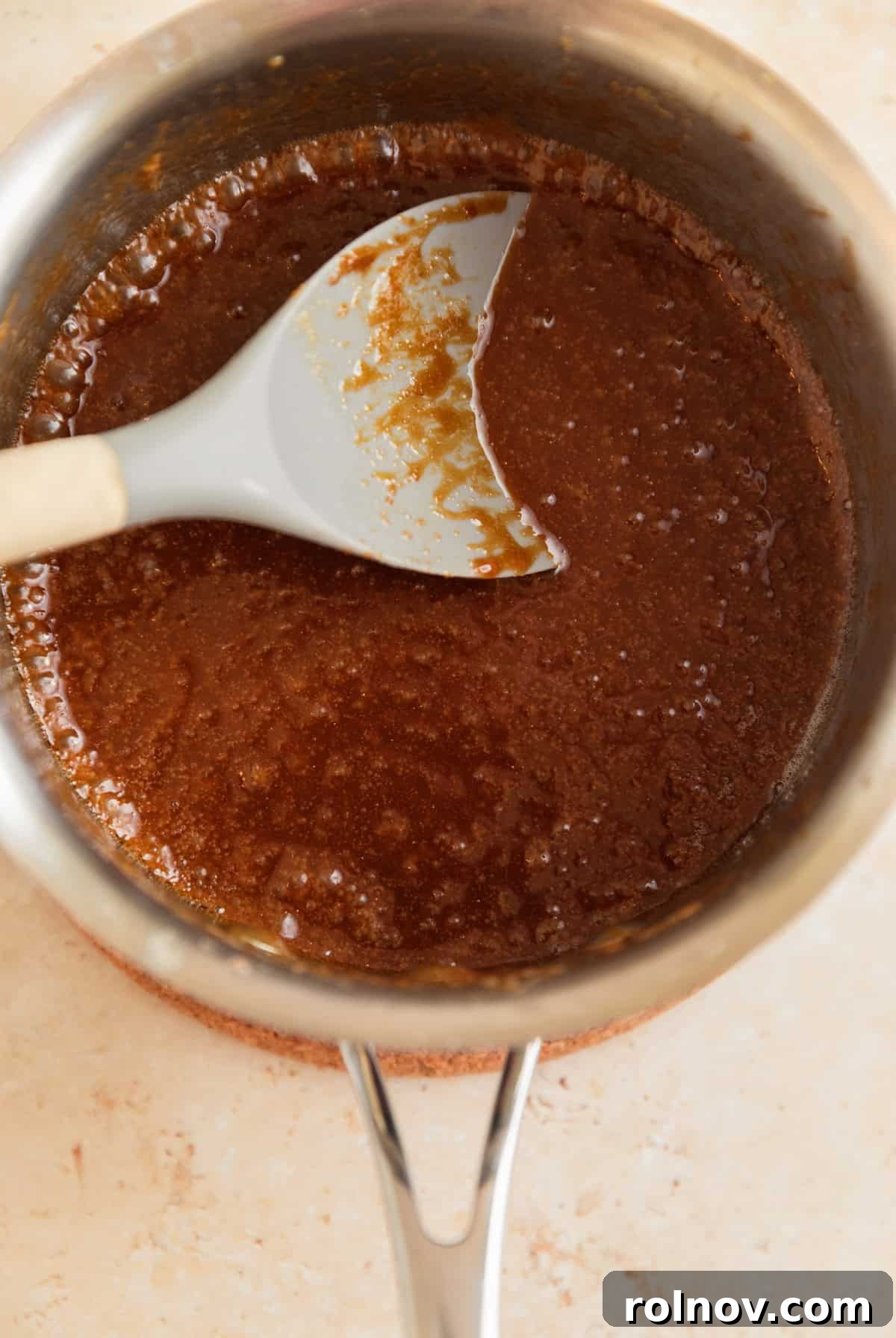 Salty Sweet Pretzel Toffee Crunch 7 The caramel mixture vigorously bubbling in a saucepan, beginning to thicken and turn a rich amber color, with a spoon stirring it.