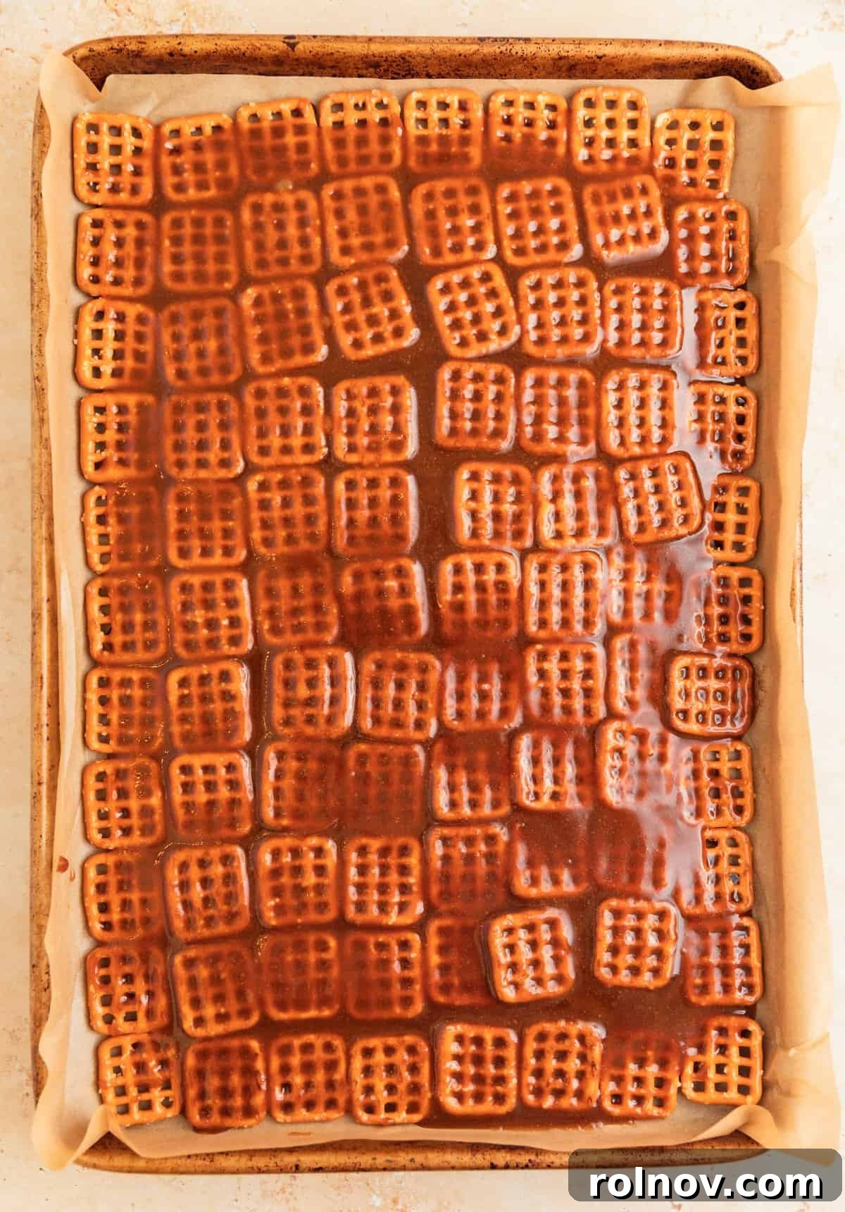 Salty Sweet Pretzel Toffee Crunch 8 Hot, freshly cooked caramel being carefully poured over the neatly arranged pretzels on a parchment-lined baking sheet.