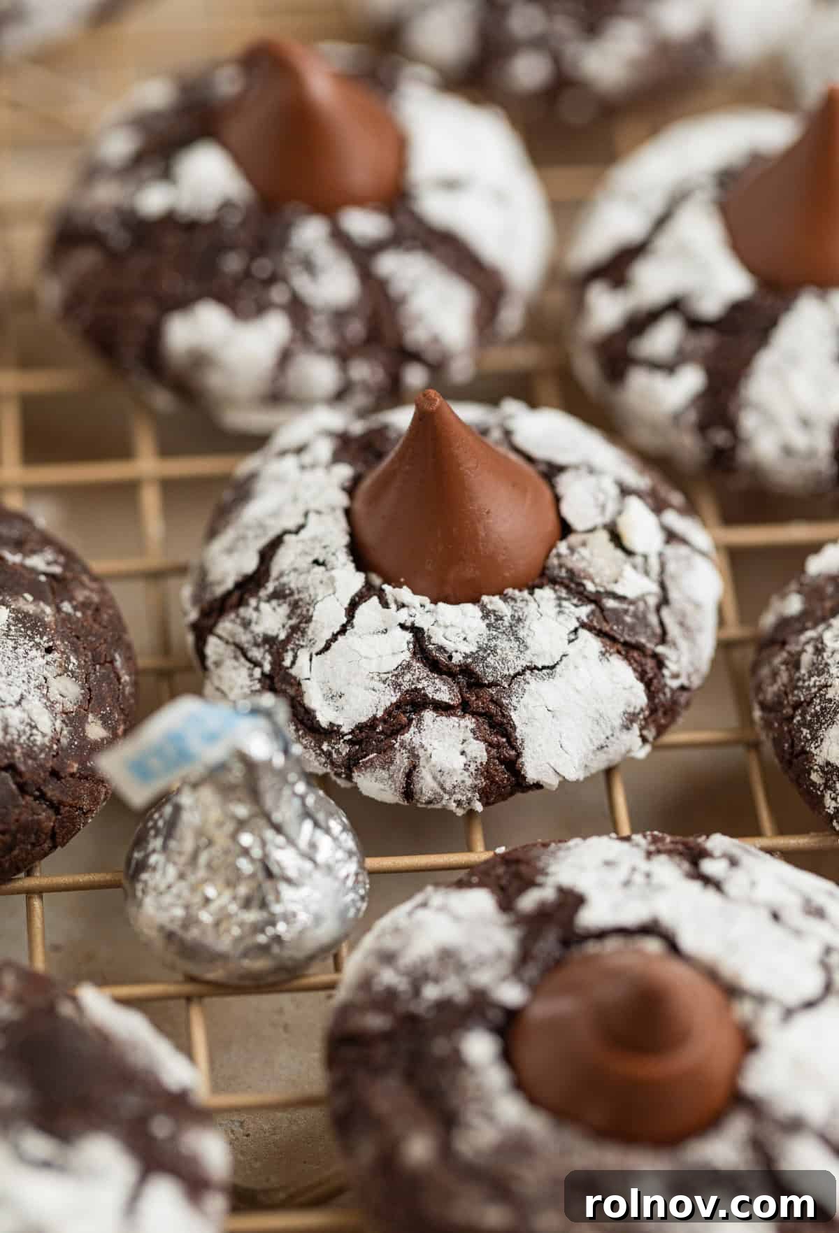 Velvet Chocolate Crinkle Blossoms 2 Chocolate crinkle cookies with hershey kiss centers on wire rack.