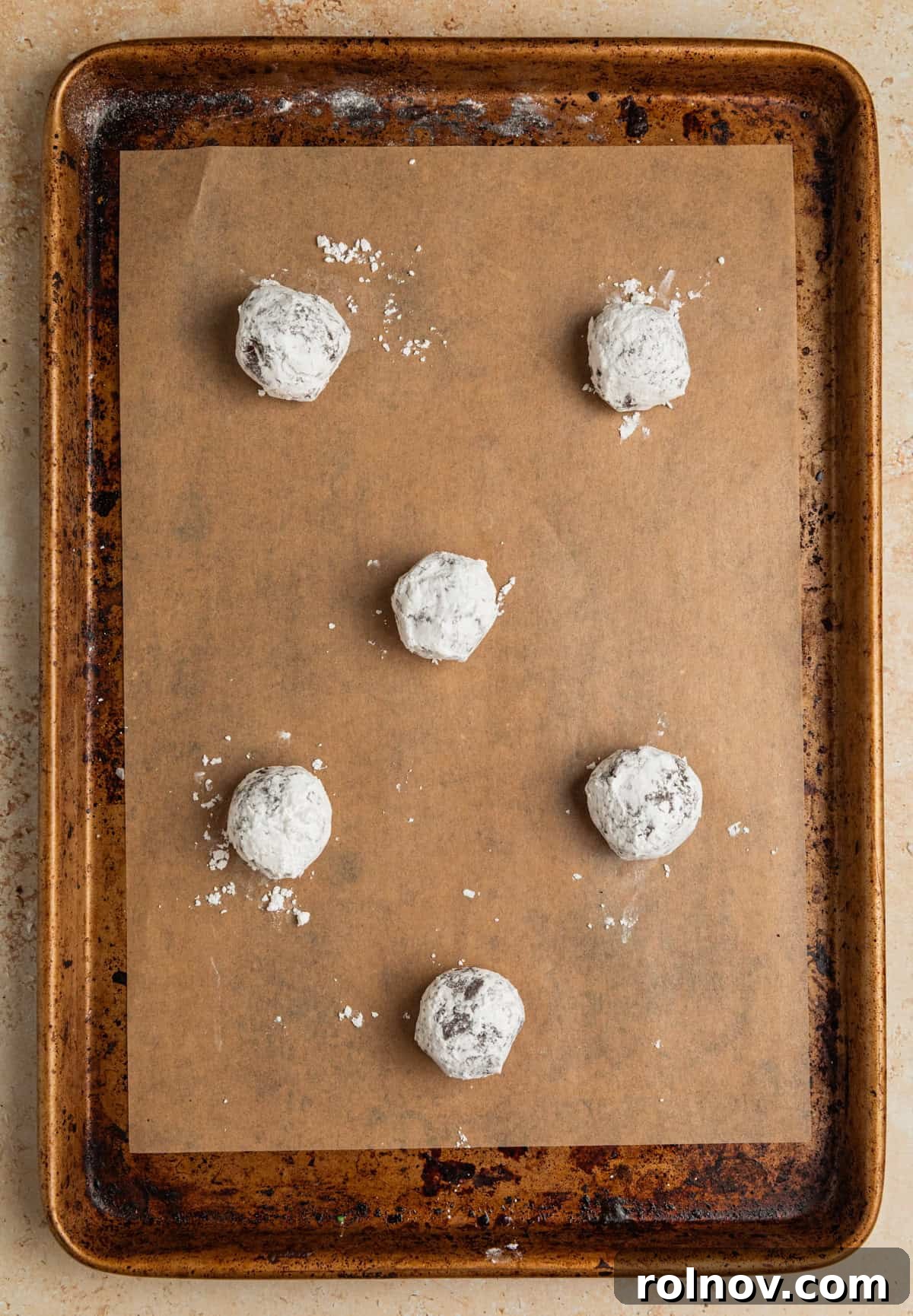 Velvet Chocolate Crinkle Blossoms 7 Powdered sugar covered chocolate cookie dough balls on parchment lined pan.