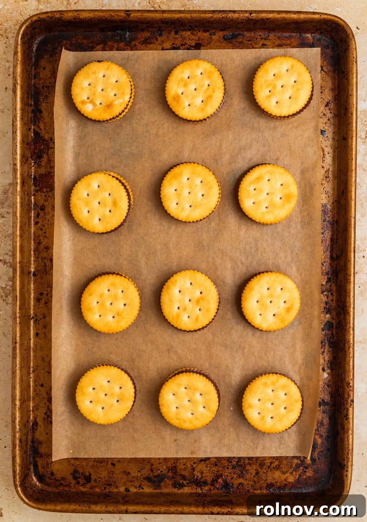 Crackers topped on melted chocolate peanut butter cut candy on parchment lined cookie sheet.