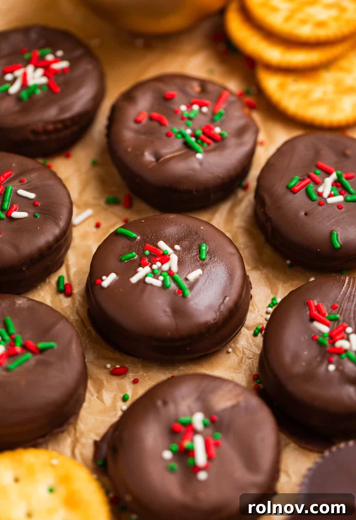 Chocolate dipped cracker cookies with red and green sprinkles on top.