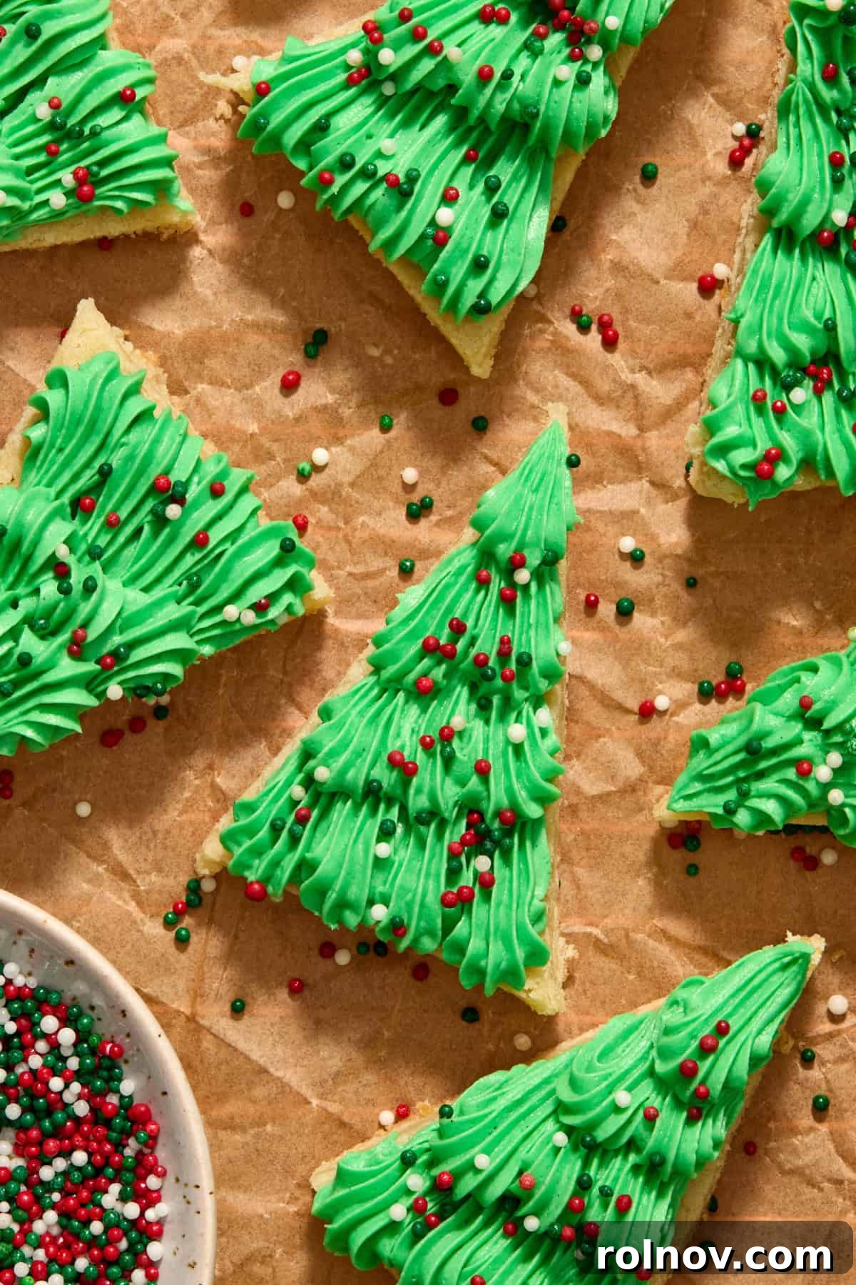 Christmas sugar cookie bars iced with green frosting piped on with sprinkles.