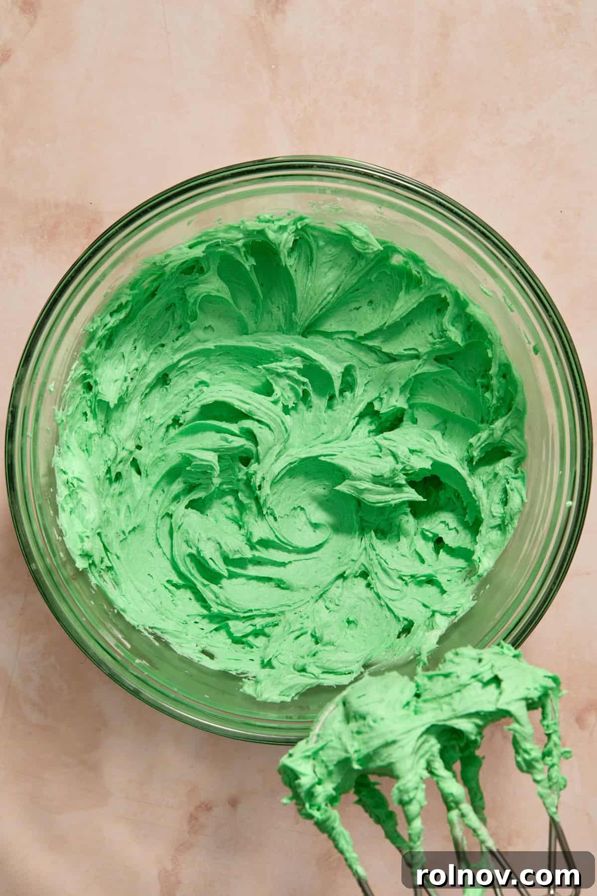 Vibrantly green buttercream frosting in a mixing bowl, ready for decorating.