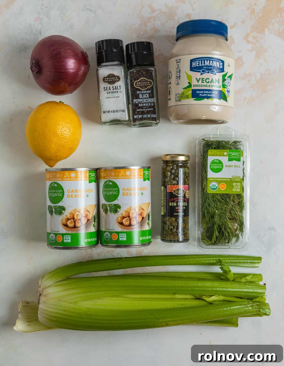 Plant-Based Chickpea Tuna Salad 4 Ingredients for vegan chickpea tuna salad laid out on a kitchen counter, including canned chickpeas, vegan mayonnaise, dill, capers, and red onion.