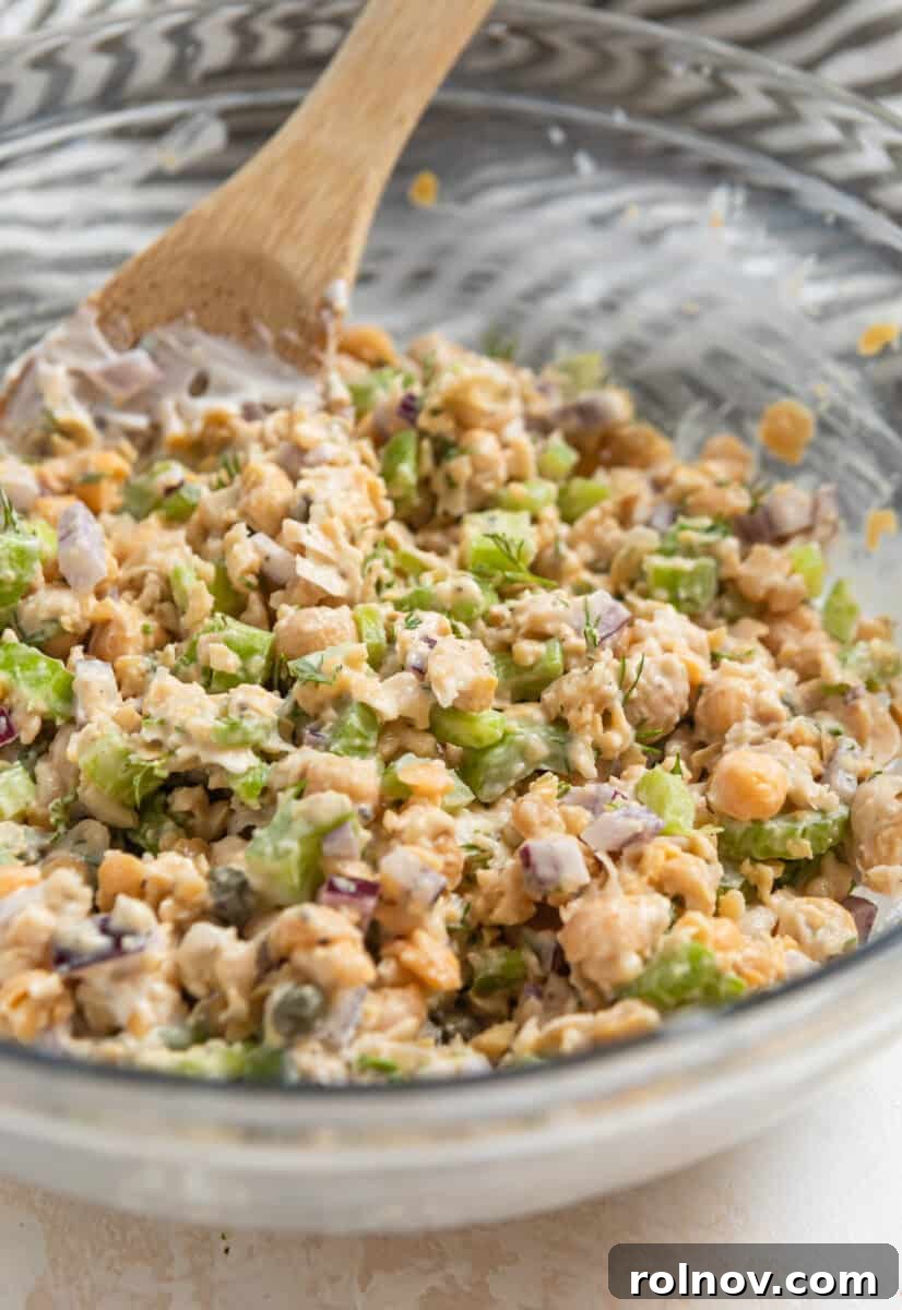 Plant-Based Chickpea Tuna Salad 7 Chickpea dill tuna salad being mixed in a bowl with a wooden spoon.