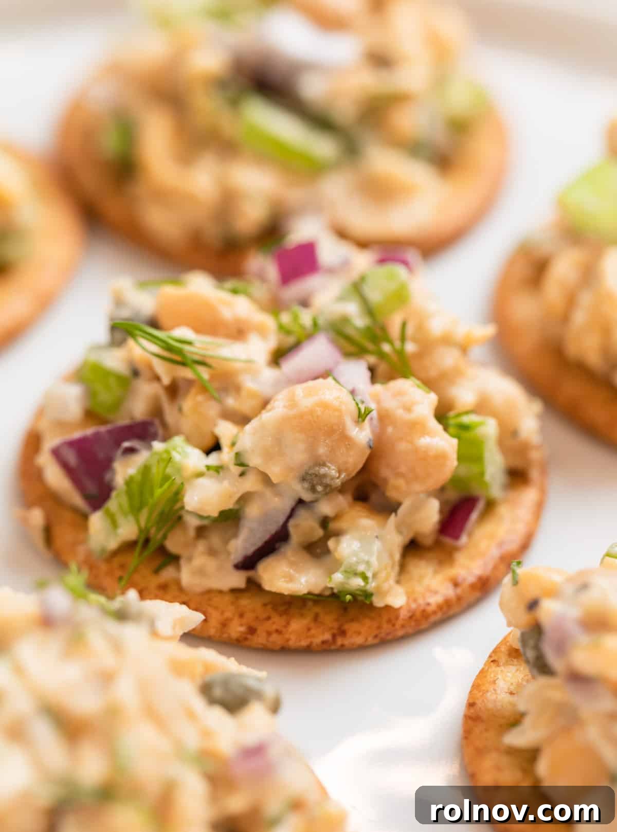Plant-Based Chickpea Tuna Salad 9 Crackers lined on a white plate with vegan tuna salad scooped on top, ready to serve as an appetizer.