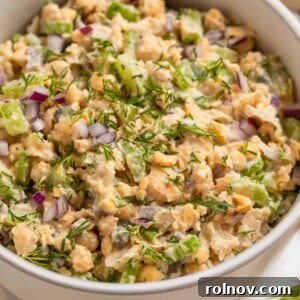 Bowl with mashed chickpea mock tuna salad topped with chopped red onion and dill.