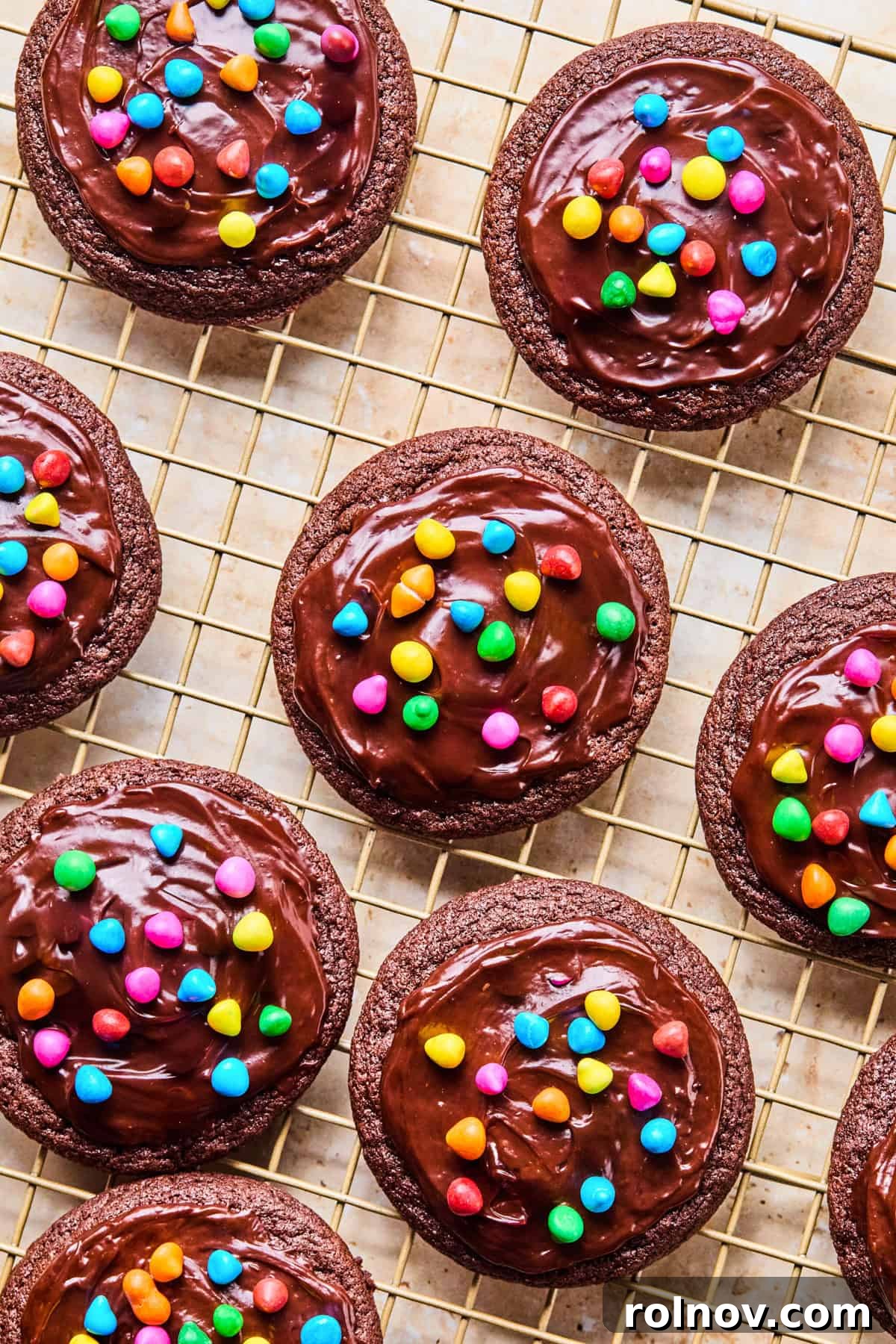 Supernova Brownie Cookies 2 Freshly baked cosmic brownie chocolate cookies cooling on a wire rack, glistening with ganache and rainbow chips.