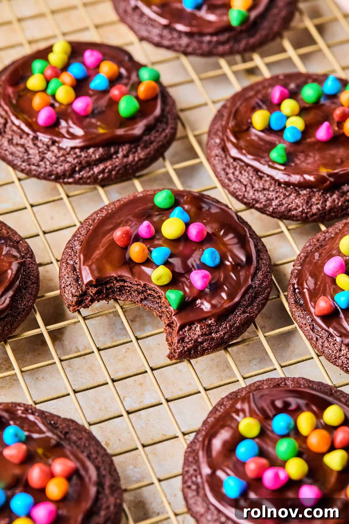 Supernova Brownie Cookies 15 Finished cosmic brownie cookies with shiny ganache and colorful rainbow chips, arranged on a wire rack.