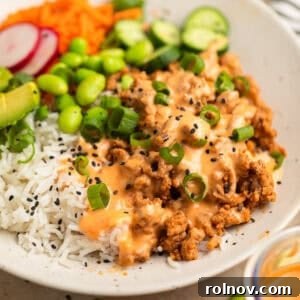 A vibrant rice bowl featuring ground turkey, creamy bang bang sauce, crisp cucumber, and shredded carrots.