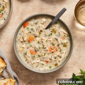 Creamy chicken wild rice soup in a bowl, garnished with chopped parsley.